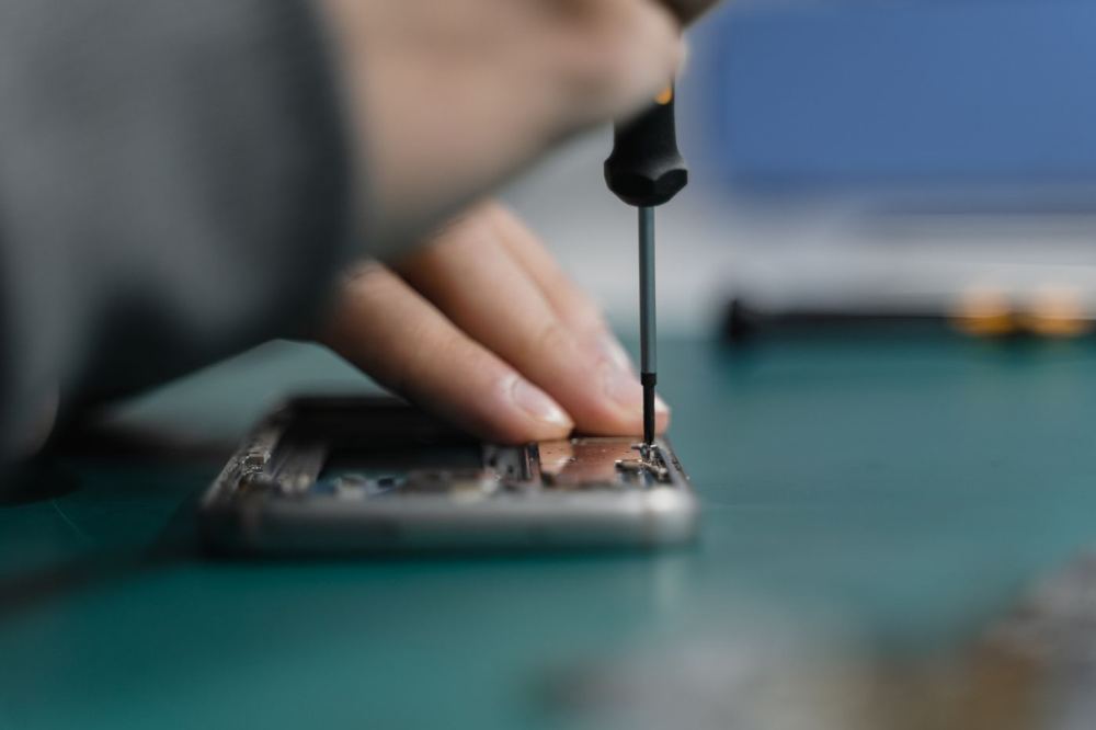 Technician opening a phone with a screwdriver